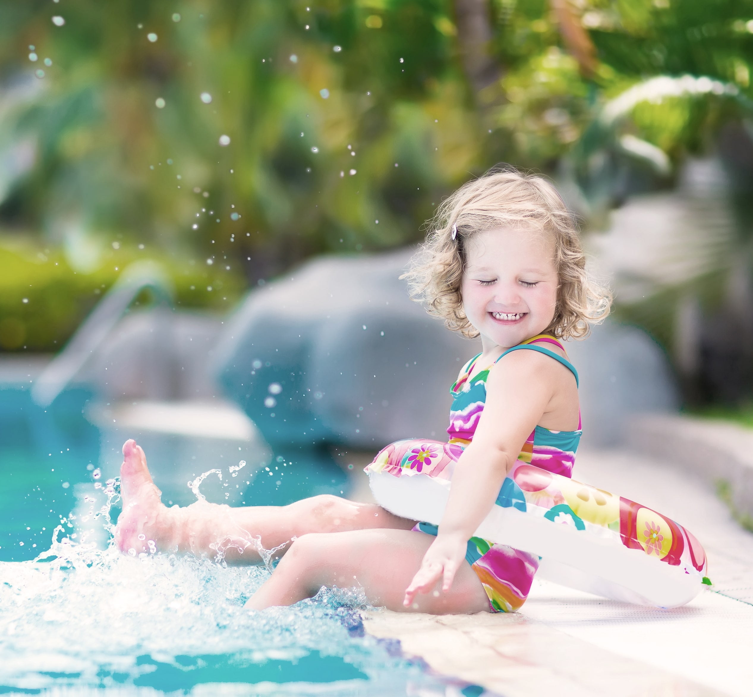 Little Girl playing in a swimming pool while being watched by her nanny